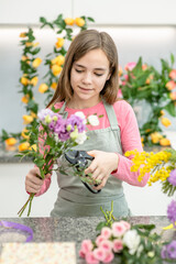 Young girl cutting flower with scissors  at flower shop. Hobby and leisure concept