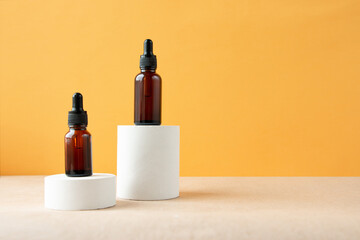 A cosmetic bottle with an amber glass dropper sits on a concrete pedestal. Natural beauty products....