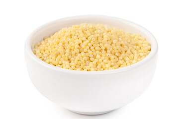 Raw dried uncooked millet seeds with white ceramic plate and light background macro
