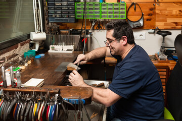 goldsmith sands a silver ring on the workbench.