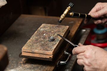 goldsmith jeweler soldering a silver ring on the workbench with a soldering.
