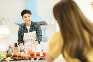 Husband slicing vegetables to prepare breakfast. With a young wife supporting him In a romantic atmosphere