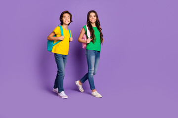 Fototapeta premium Full size photo of cheerful boy and girl go school wear backpack education isolated on violet color background