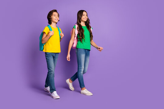 Full body profile side photo of two cheerful kids happy positive smile go walk school carry bags isolated over violet color background