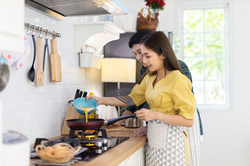 Portrait young couple in love helping to cook In a romantic atmosphere at home and looking at camera with smile face.