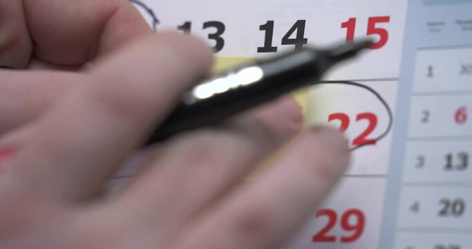The hand circles the weekend days on the calendar. the hand sticks a reminder on the calendar about the meeting. meeting. an important event. reminder card. Closeup on a calendar with DAY OFF being