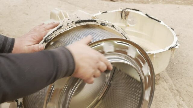 professional craftsmen is rotating disassembled drum of washing machine. checking what is the problem. washing machine repair concept. plumber at work