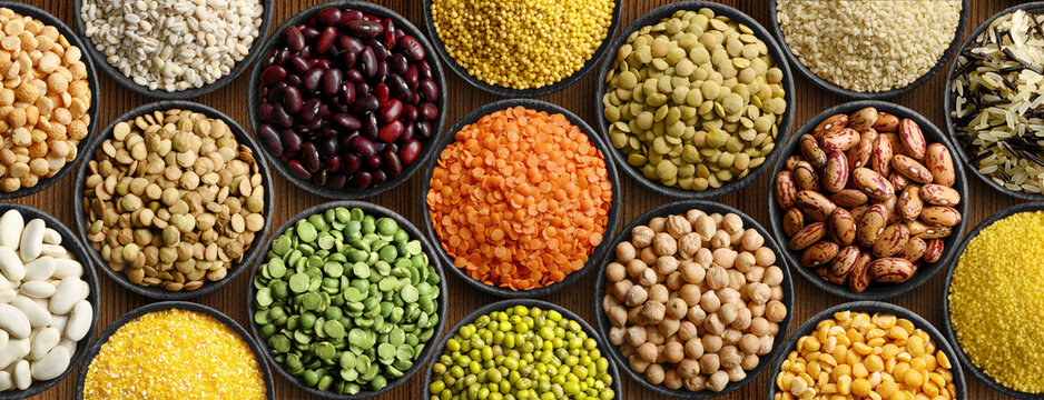 Various colorful legumes and cereals in black bowls background.