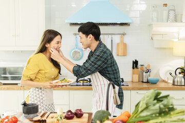 Portrait young couple in love helping to cook In a romantic atmosphere at home and looking at camera with smile face.