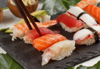 Close up of hand taking roll with chopsticks from a plate