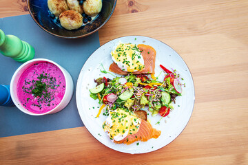 Two delicious poached eggs with salmon on toast served with mixed vegetables and lettuce in white ceramic plate