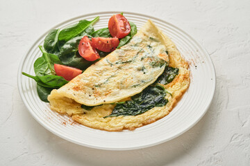 Omelet or omelette with spinach, cherry tomato and pepper seasoning on a white plate, on white background. Top view.