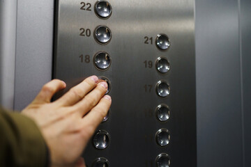 Naklejka premium Man's hand points to the elevator button. Calling the elevator from the inside.