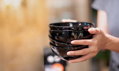 Female hand holding the stack of bowl, for keeping on the shelf.