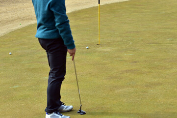 Golfer putting golf ball on the green.