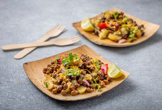 kala chana chaat with boiled potato, onion, tomato with lemon on a bamboo plate 