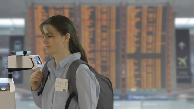 Woman scanning digital health passport on phone in airport, no need mask