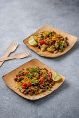 kala chana chaat with boiled potato, onion, tomato with lemon on a bamboo plate 