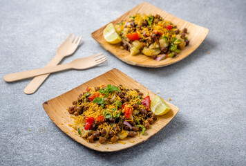 kala chana chaat with boiled potato, onion, tomato with lemon on a bamboo plate 