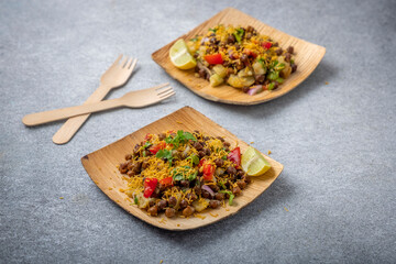 kala chana chaat with boiled potato, onion, tomato with lemon on a bamboo plate 