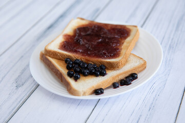 Toast with berries and jam on a light wooden background
