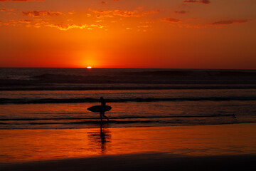 Naklejka na ściany i meble silhouette of a surfer at sunset on beach