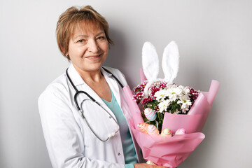 doctor woman with easter spring bouquet of flowers, colorful eggs and bunny ears