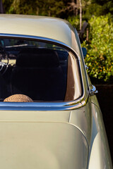 Rear window of an classic car parked in a sunny garden.