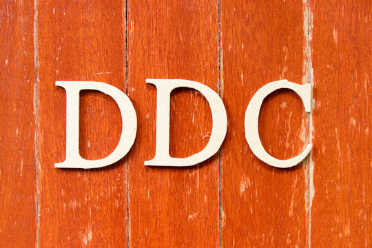 Alphabet Letter In Word DDC (Abbreviation Of Division Of Disease Control,  Direct Digital Control, Display Data Channel Or Dewey Decimal Classification) On Old Red Color Wood Plate Background