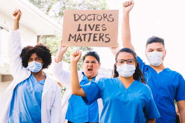 medical staff wearing face masks with hands up and holding a sign that says 