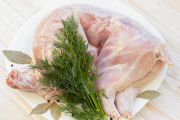 rabbit carcass meat with dill on a white plate.