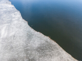 Melting ice edge on the river. Aerial drone view.