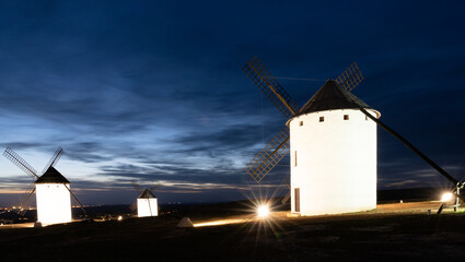 view of the historic white windmills of La Mancha above the town of Campo de Criptana at sunset