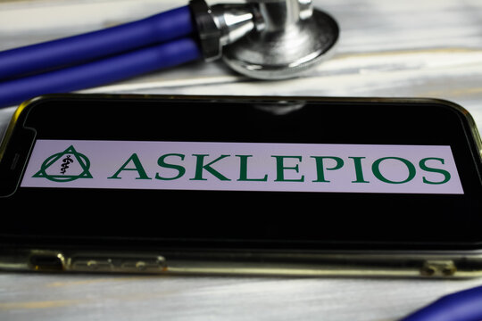 Viersen, Germany - March 1, 2021: Closeup of smartphone screen wit logo lettering of german hospital operator company asklepios on wood table