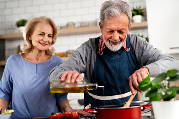 Senior woman and man cooking in the kitchen. Happy husband and wife preparing delicious food at home.