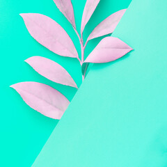 Trendy neon summer tropical fashion concept with pastel pink leaves on a bright mint green background. Minimal surrealism flat lay composition with copy space.