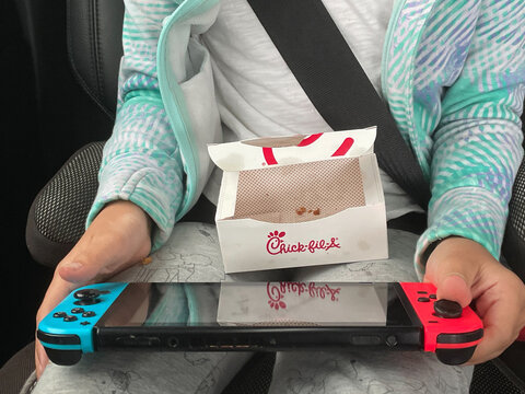 Child Eating Chick-fil-A Fast Food And Playing Video Games In Car On March 31, 2021 In Asheville, North Carolina