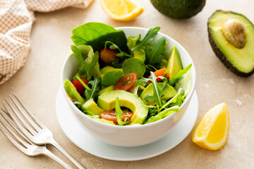 Heathy food salad bowl. Avocado spinach salad with lemon juice and olive oil.