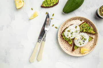 Avocado Sandwich with Poached Egg and avocado on toasted bread. Delicious breakfast or snack on a light background, top view