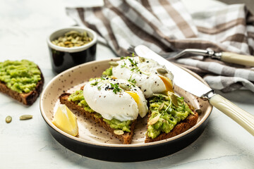 Avocado Sandwich with Poached Egg and avocado on toasted bread. Delicious breakfast or snack on a light background, top view