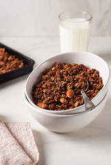 Homemade chocolate granola in a white plate with milk on a light background. Healthy breakfast