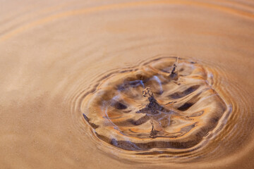 A splash of water on a macro shot of a sandy bottom under water