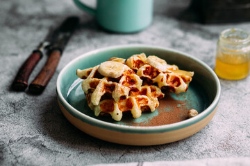 Belgian waffles with banana and honey on a turquoise plate