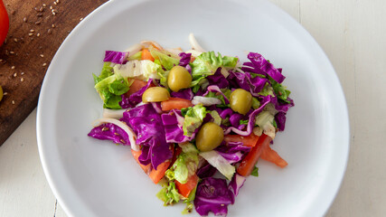 Flat lay view of a fresh mediterranean style salad, placed on top of a white table