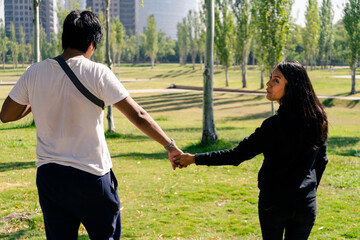 Young couple walking through the park holding hands. Romanticism concept