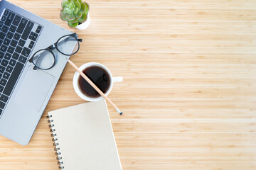 flat lay composition with notebook, pen, coffee, plant, laptop on wood background. top view