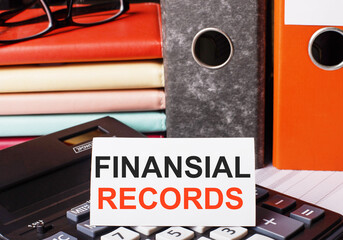 Naklejka premium Next to the diaries and folders with documents on the calculator there is a white card with the inscription FINANCIAL RECORDS