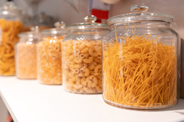 Cuisine and food. A row of glass jars with different types of pasta. Close up