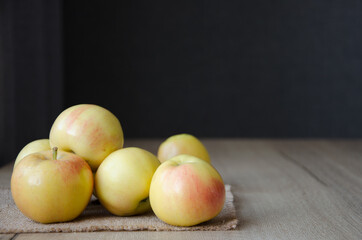Yellow apples on a jute napkin on a wooden table
