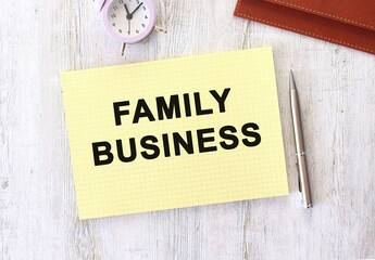 FAMILY BUSINESS text written in a notebook lying on a wooden work table.